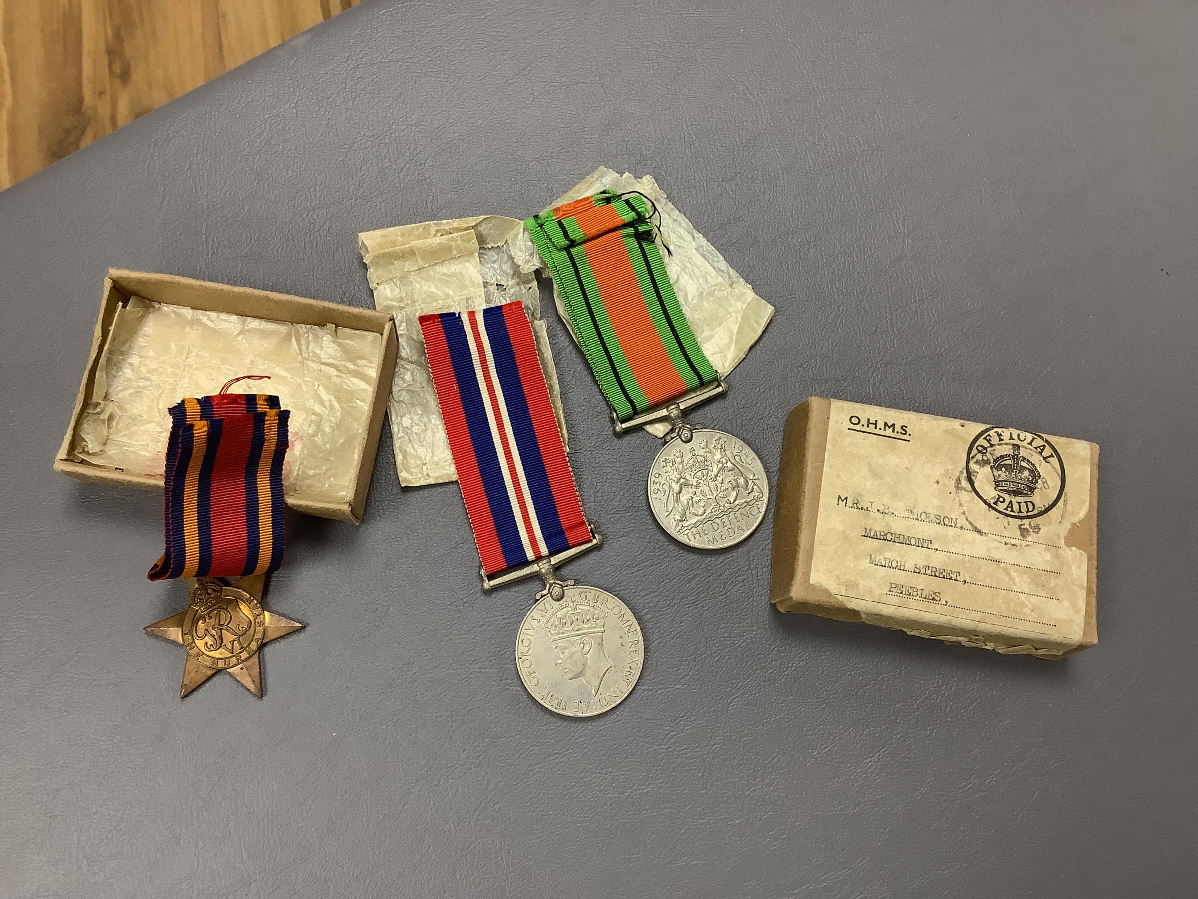 A WWII medal trio comprising a Burma Star, The Defence Medal and the 1939-1945 Medal, contained within their original card issue box, together with a Gurkha cap badge and a few other items. Condition - fair to good.